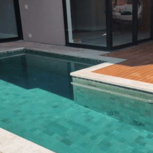 piscina com pedra hijau, borda travertino e deck de madeira